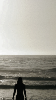 Silhouette of a woman standing at the shoreline