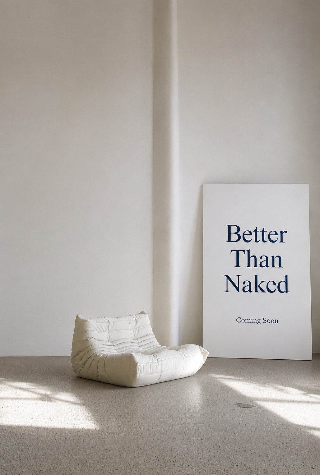 Better Than Naked poster next to a cream lounge chair